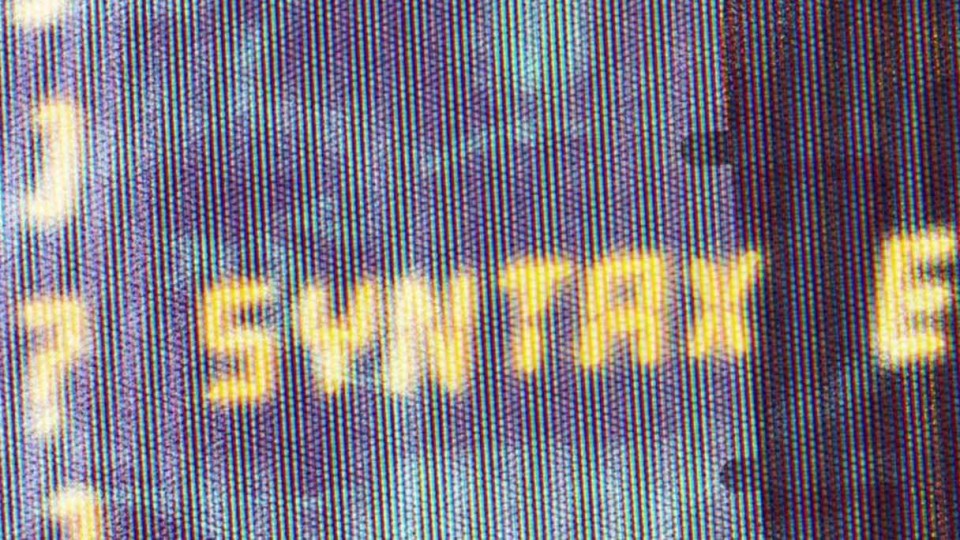 An extreme closeup of an old monitor that says syntax error.