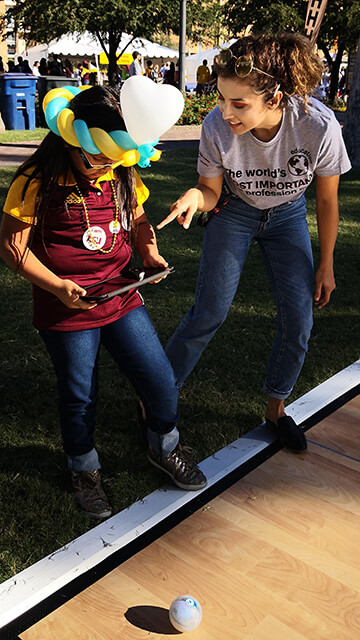 An Educational Technology Champion helps a girl run a Sphero robot