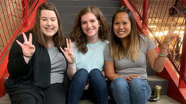 Hannah, Hannah and Christina show the pitchfork sign