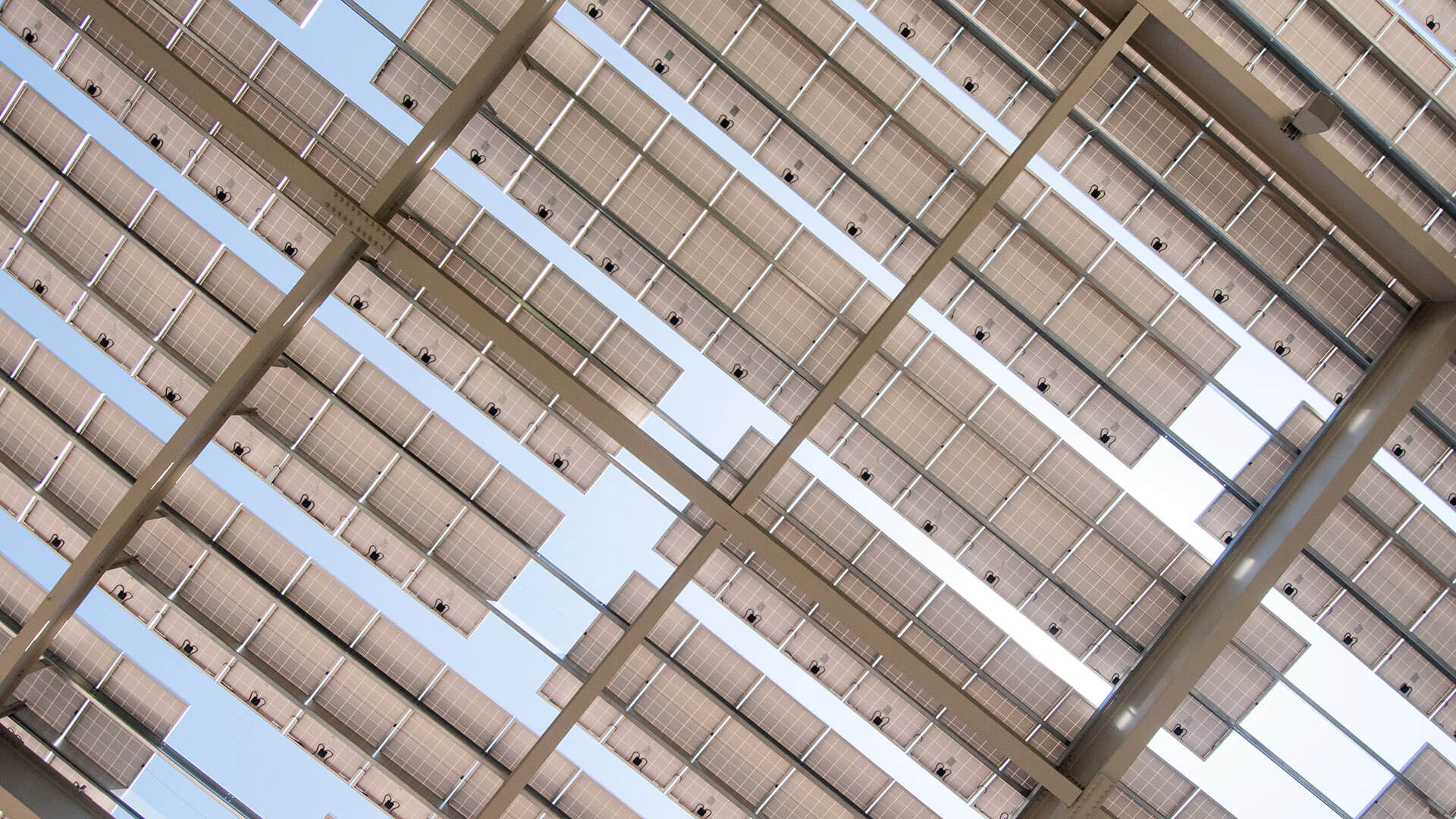 
		Looking up at the sky from underneath a large solar array		