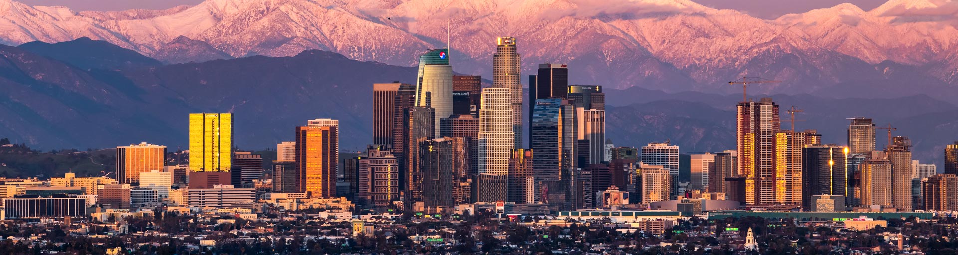 
		A view of downtown Los Angeles near sunset with Mount Baldy in the background.		